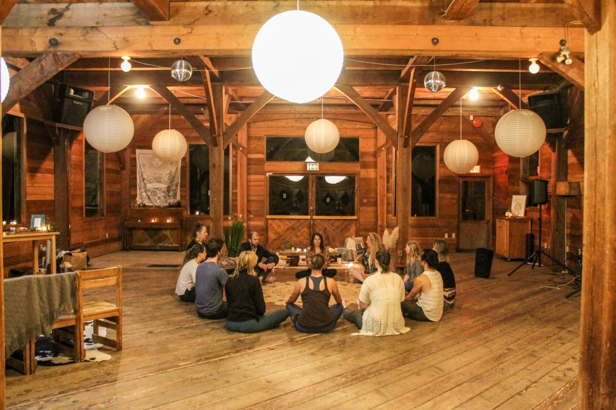 A sharing circle in a wooden hall lit by paper lanterns