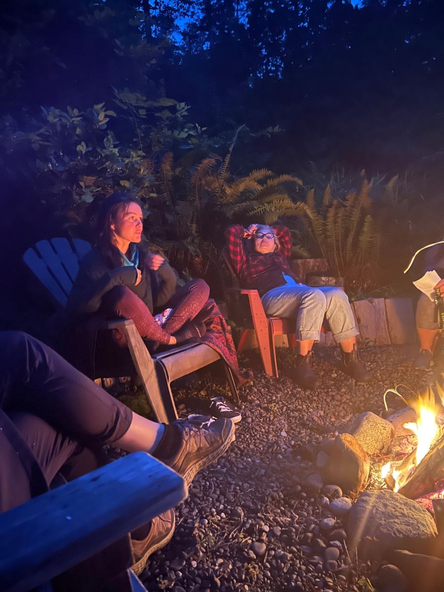 Friends relaxing around an evening campfire in the forest