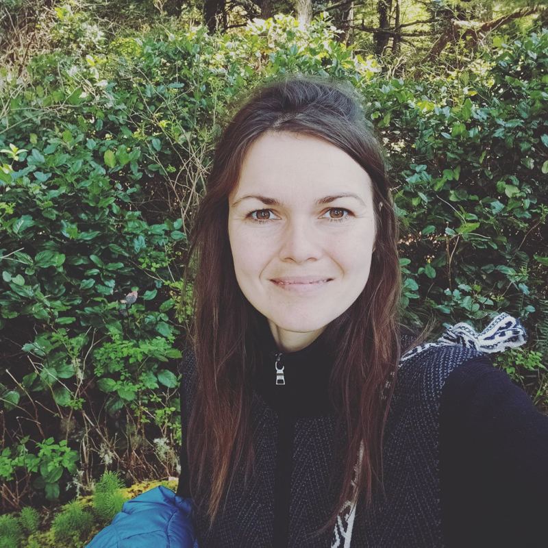 Sasha smiling in a green forest